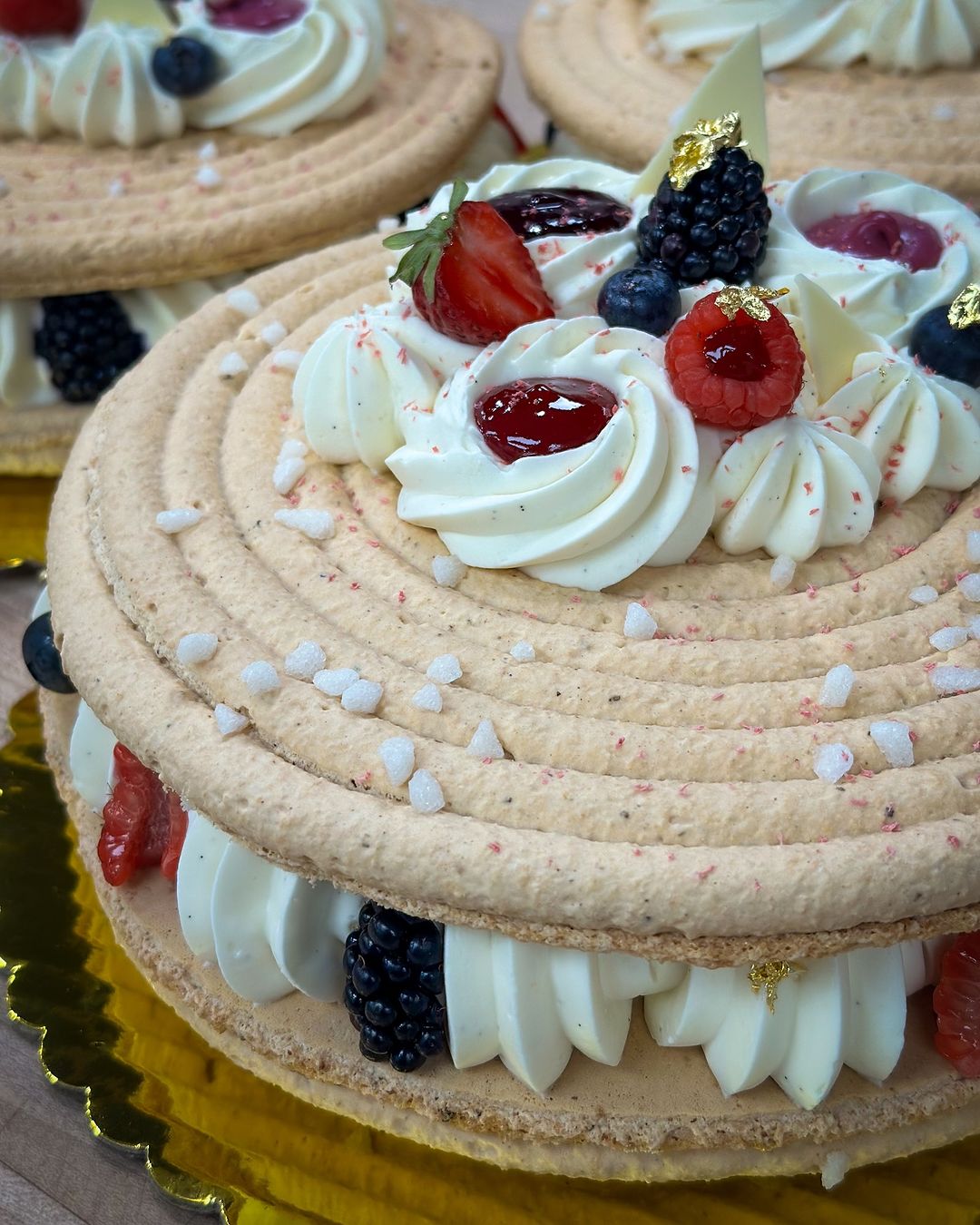 A delectable cake topped with fresh berries and cream, featuring a rich layer of pastry cassis fruit for added flavor.