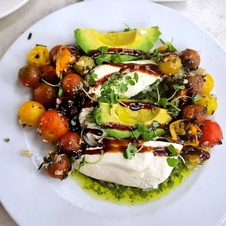 Plate with tomatoes, avocado, and cheese - perfect ingredients for homemade flavored vinegar for salads and marinades.