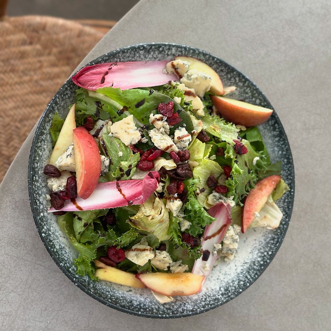 A vibrant salad featuring fresh apples, crisp radishes, and crumbled blue cheese, artfully arranged in a bowl.