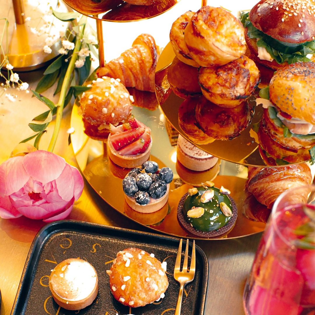 A beautifully arranged table featuring an array of showstopping pastries surrounded by vibrant flowers.