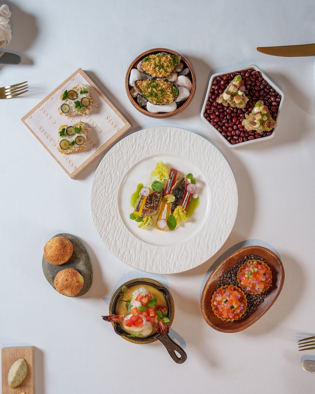 A table set with many plates of food, showcasing a sophisticated main course.