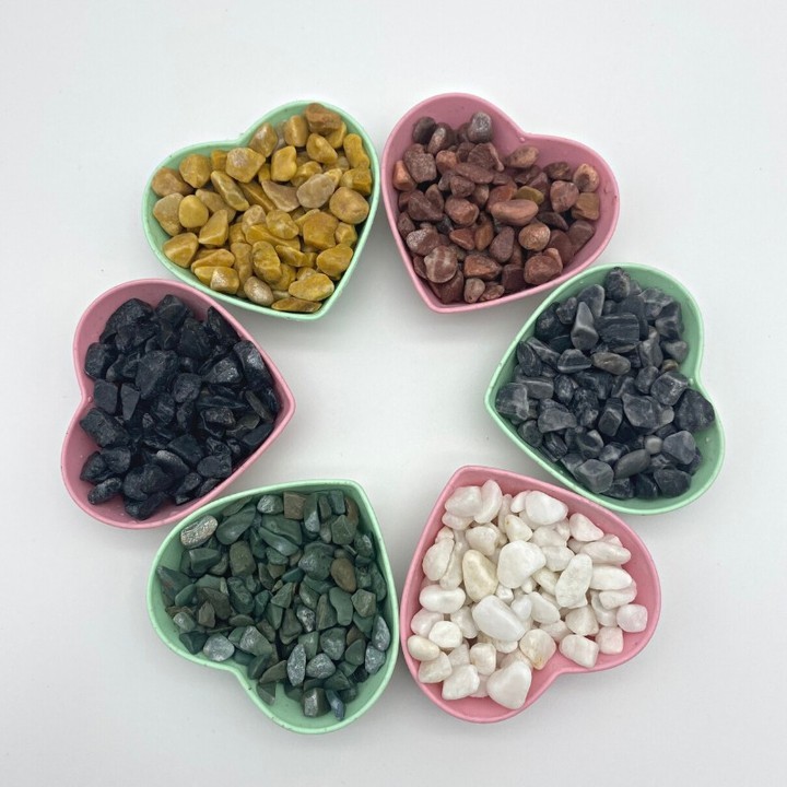 A heart-shaped bowl filled with various washed stones in vibrant colors, showcasing nature