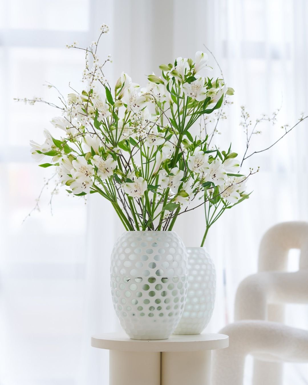 White Alstroemeria arrangement in a white vase on a table.