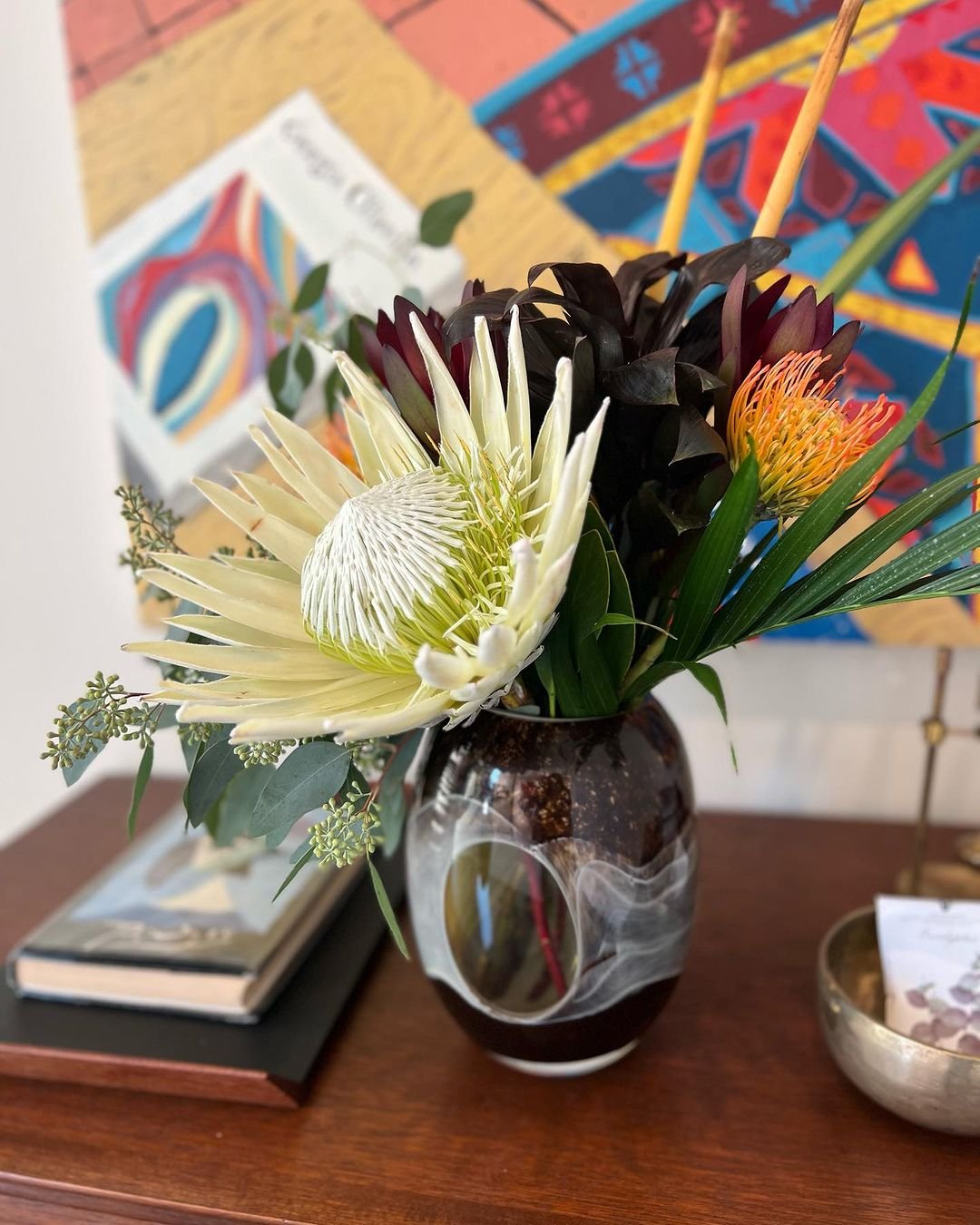 Table setting with a vase of Protea flowers.