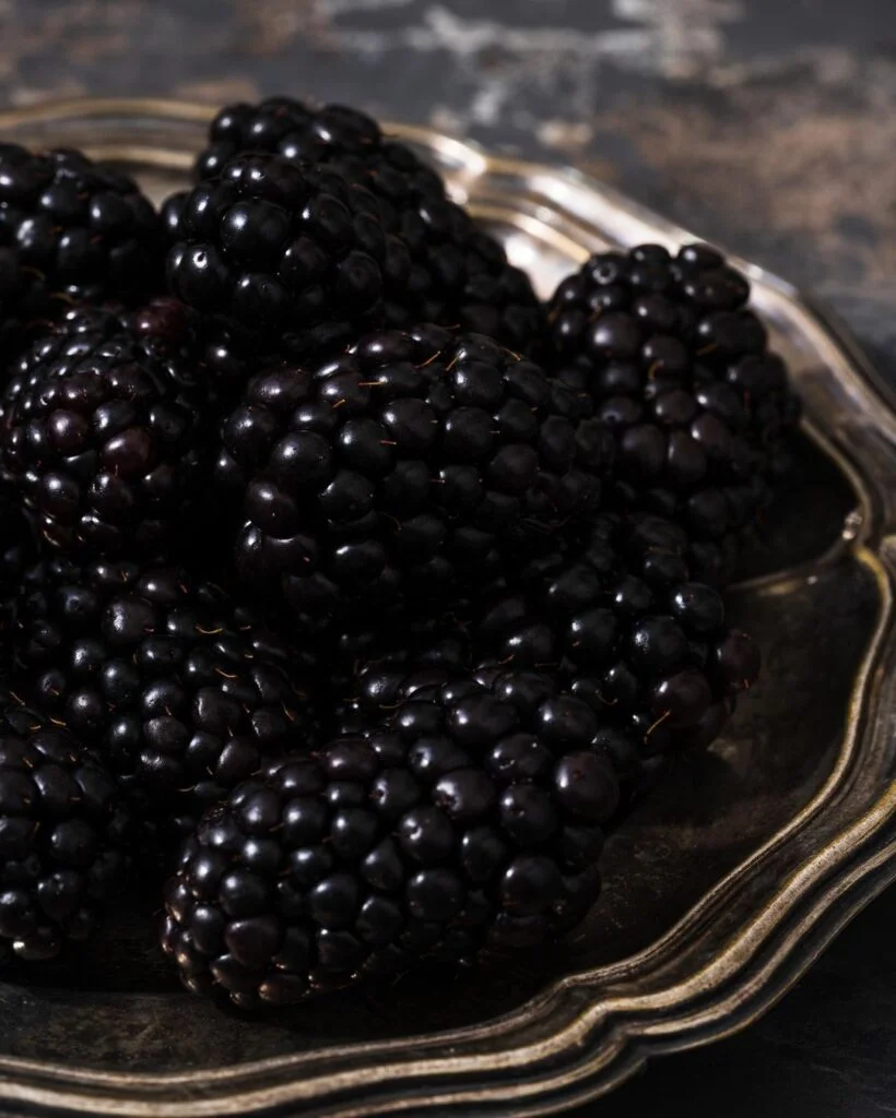 A blackberry is a juicy, dark purple to black fruit composed of small, tart berries clustered together.