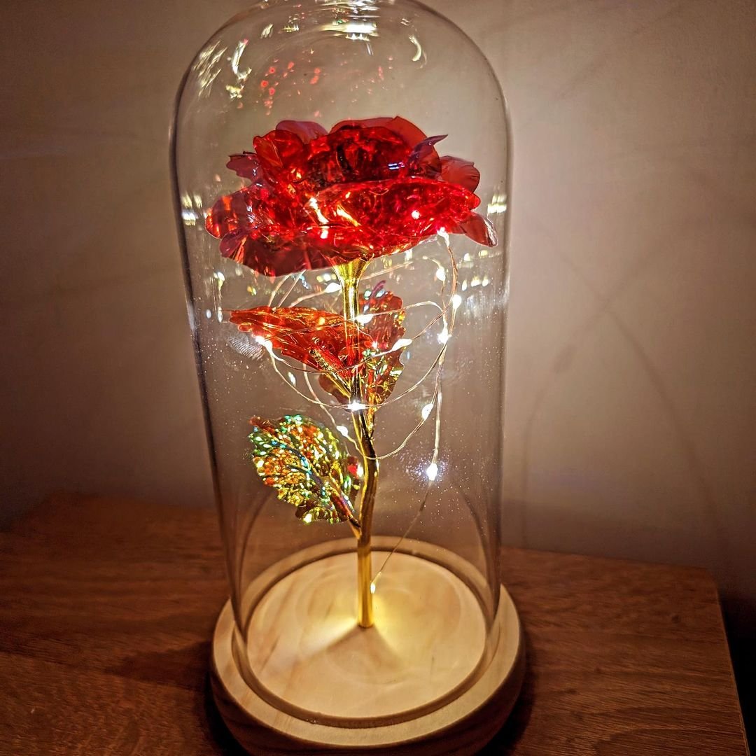 A glowing red rose under a glass dome, representing Belle's Enchanted Rose, capturing the essence of timeless beauty.
