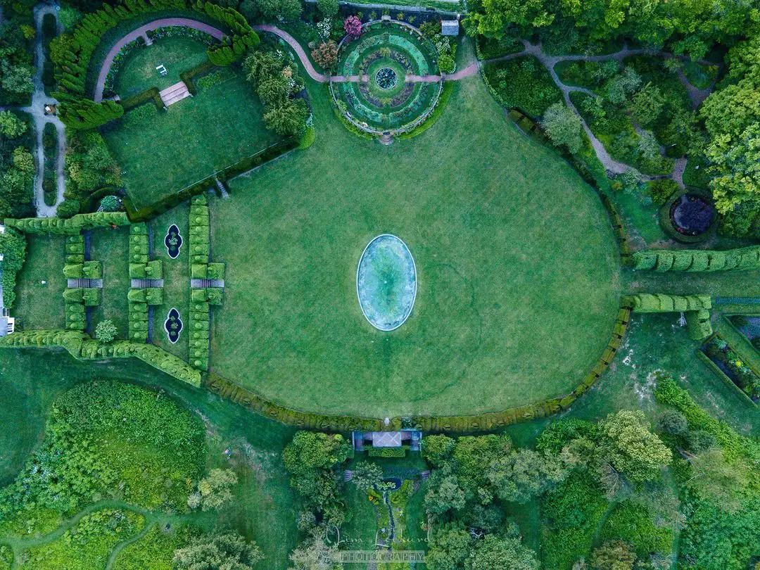 Overhead perspective of Fantasyland Topiary Garden showcasing a circular pond at the center, surrounded by meticulously shaped plants.