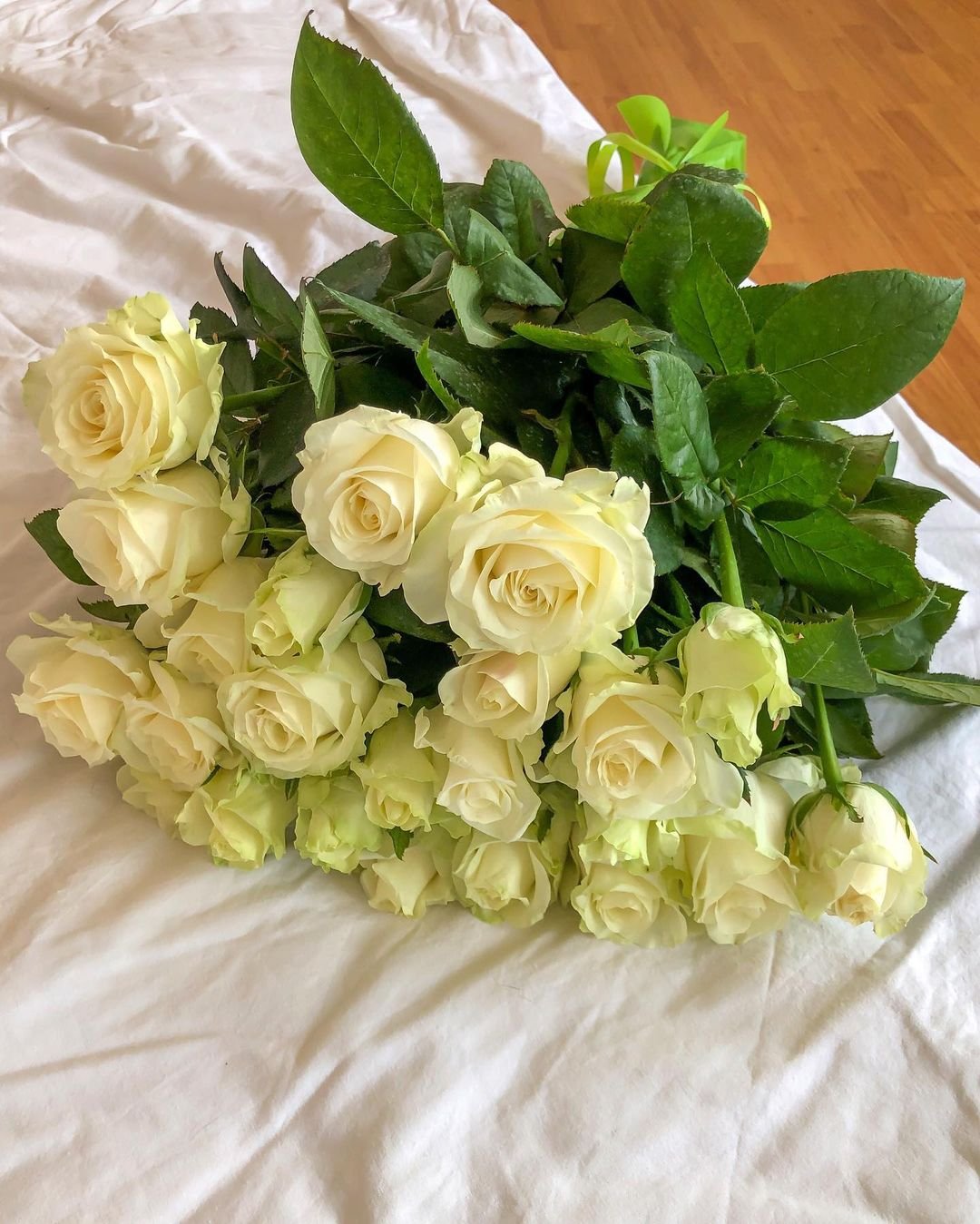  A cluster of white roses elegantly arranged on a soft bed, showcasing their delicate petals and serene beauty.