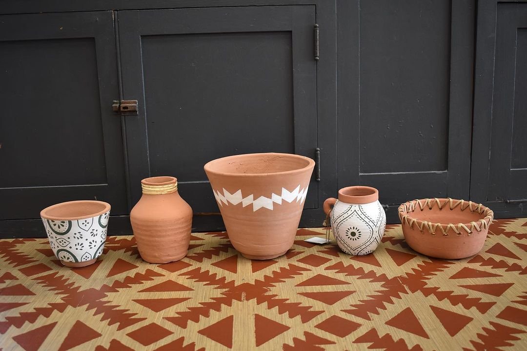 A collection of terracotta planters arranged neatly on a floor, showcasing their earthy tones and textures.