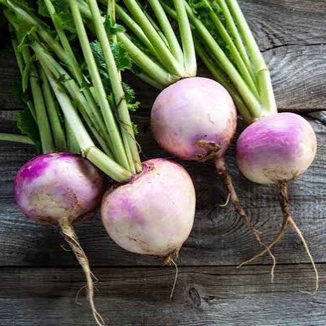 A cluster of fresh turnips displayed on a rustic wooden table, showcasing their vibrant colors and earthy texture.